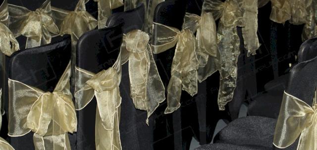 Wear It For Autism https://d1hcs5uofxldvl.cloudfront.net/furniture-hire-uk/article_additional/anna-kennedy-online13/anna-kennedy-online13-740x350.jpg - Banquet chairs with black covers and gold bows | HC108