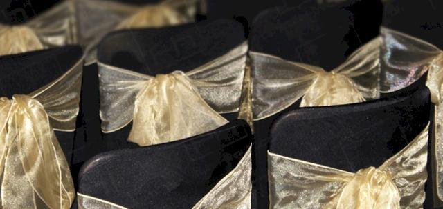 Wear It For Autism https://d1hcs5uofxldvl.cloudfront.net/furniture-hire-uk/article_additional/anna-kennedy-online18/anna-kennedy-online18-740x350.jpg - Smart black chair covers & gold bows for charity evening.