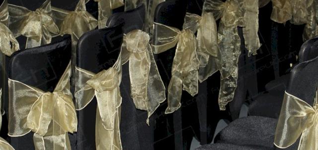 Wear It For Autism https://mill-media.s3.eu-west-2.amazonaws.com/furniture-hire-uk/article_additional/anna-kennedy-online13/anna-kennedy-online13-740x350.jpg - Banquet chairs with black covers and gold bows | HC108