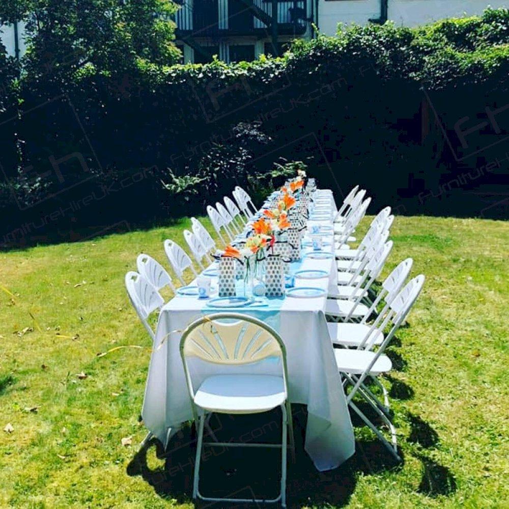 Hire rectangular trestle tables and folding chairs for an outdoor baby shower event.